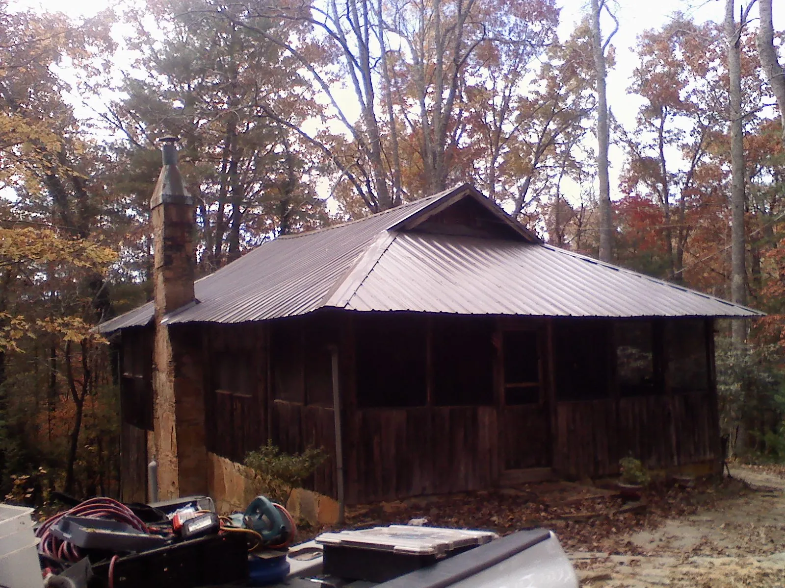 Brown metal hip roof on an old cabin with a stone chimney in Kingston