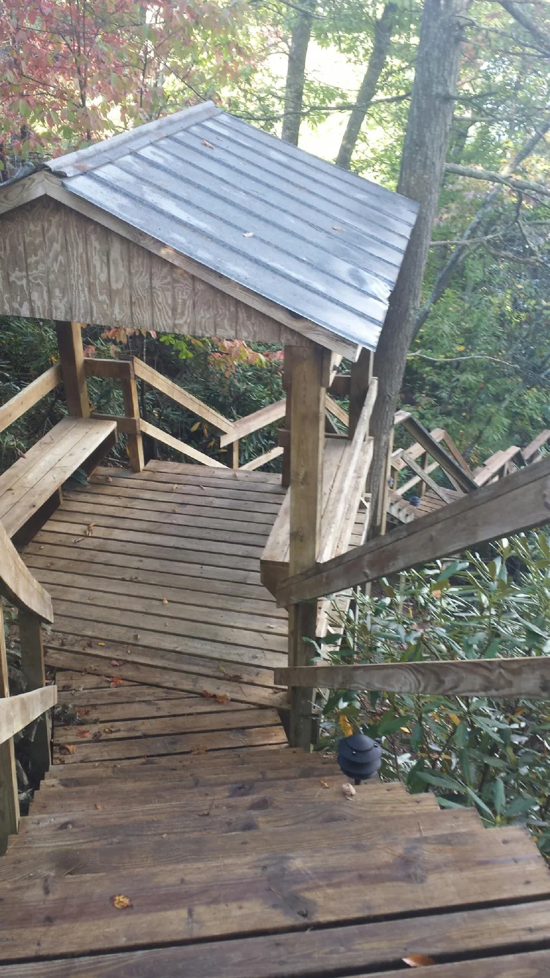 Metal roofed shelter over wooden steps on a wooded walkway — Skylight Repair & Installation work by our crew in Kingston
