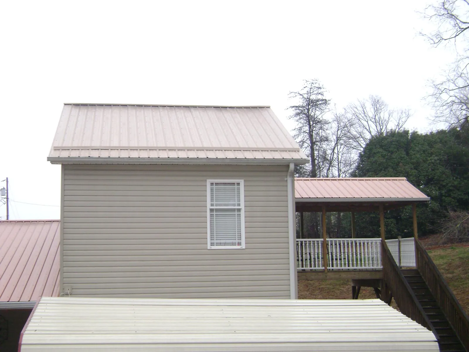 Tan metal roofs on a two story addition and attached porch, from a Roof Replacement job in Kingston